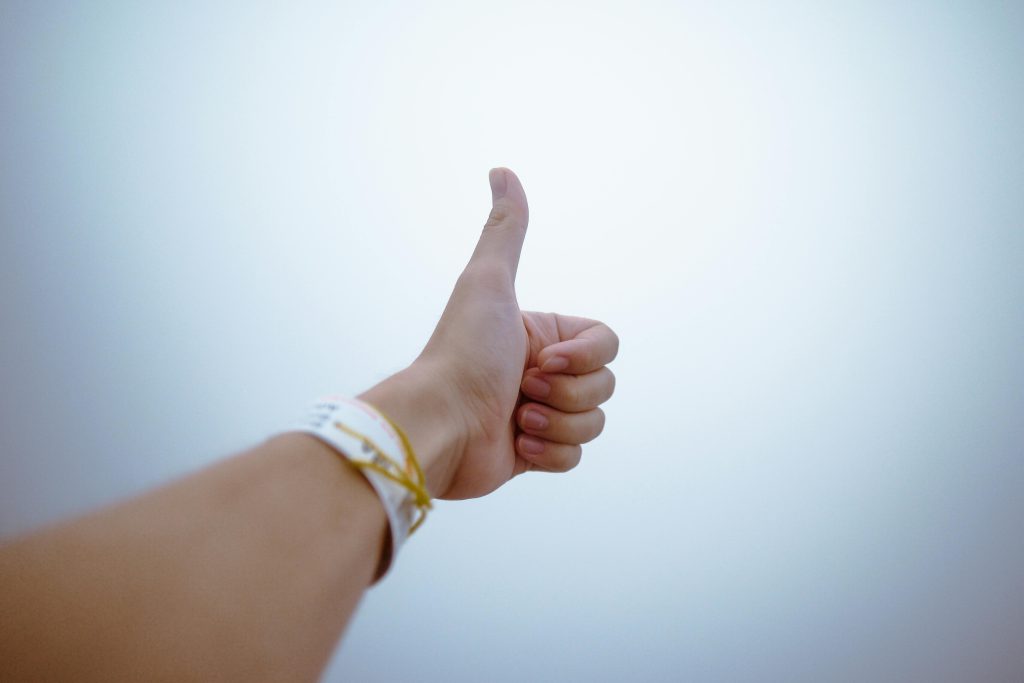 A hand giving a thumbs up gesture symbolizes approval and positivity.